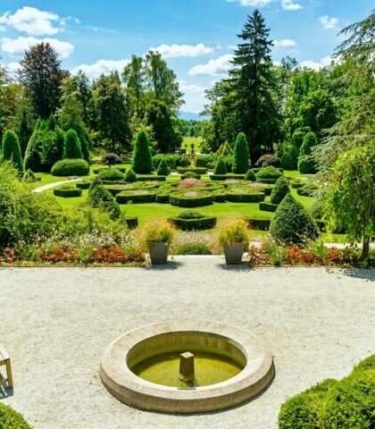 Beautiful green landscape with hedge shapes and trees in amazing park on sunny day in spring.